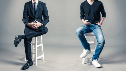 Foto zum Thema Imagegestaltung-Entfaltung, 2 Männer auf Hockern (Kopf nicht zu sehen - einer im Anzug, der andere in Jeans und schwarzem t-Shirt